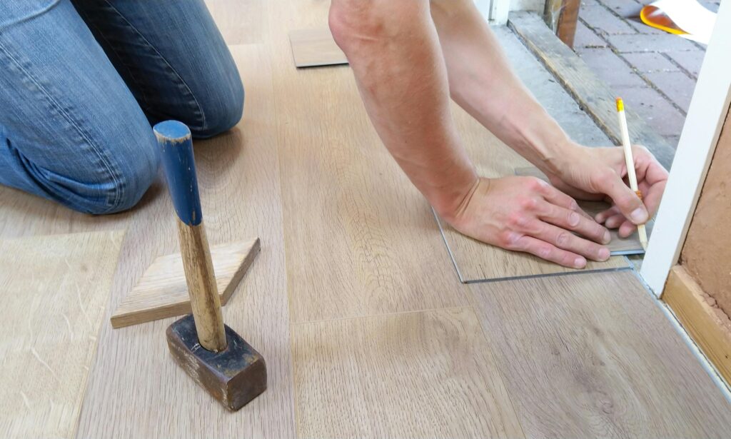 floor-flooring-hand-man-1388944-1388944 A craftsman carefully measures and marks wooden floor panels for precise installation.
